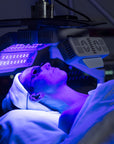Person receiving LED light therapy under a blue light device.