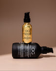 Two bottles of hair care products, one black and one gold, on a beige background.