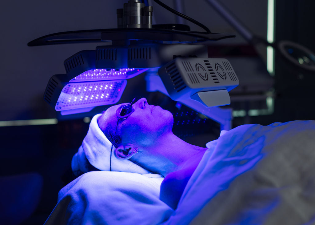 Person receiving LED light therapy under a blue light device.
