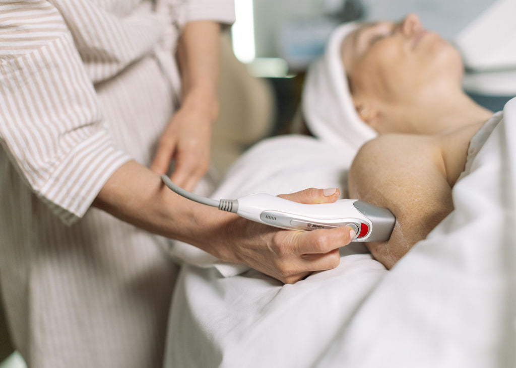 Person receiving a medical procedure with a handheld device in a clinical setting