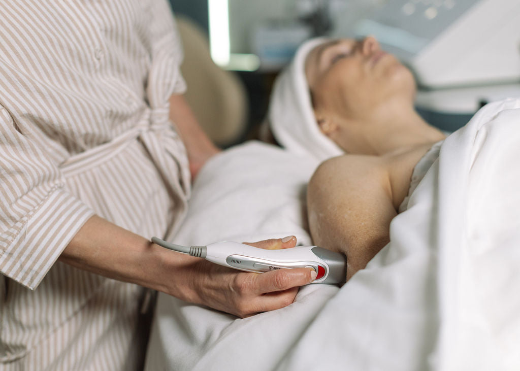 Person receiving a facial treatment with a device held by another person.
