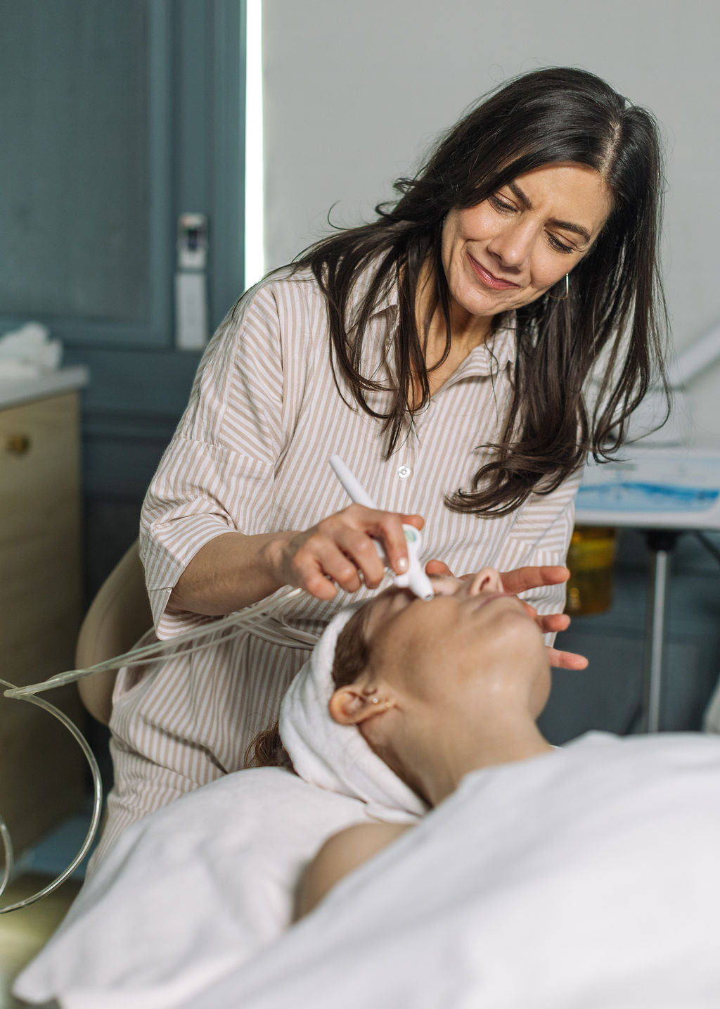 Woman performing a facial treatment on another woman in a clinical setting at Geri G. Beauty.