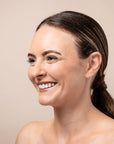 Woman with a ponytail smiling against a beige background
