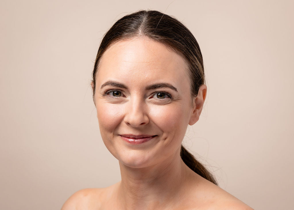 Woman with a neutral expression against a beige background